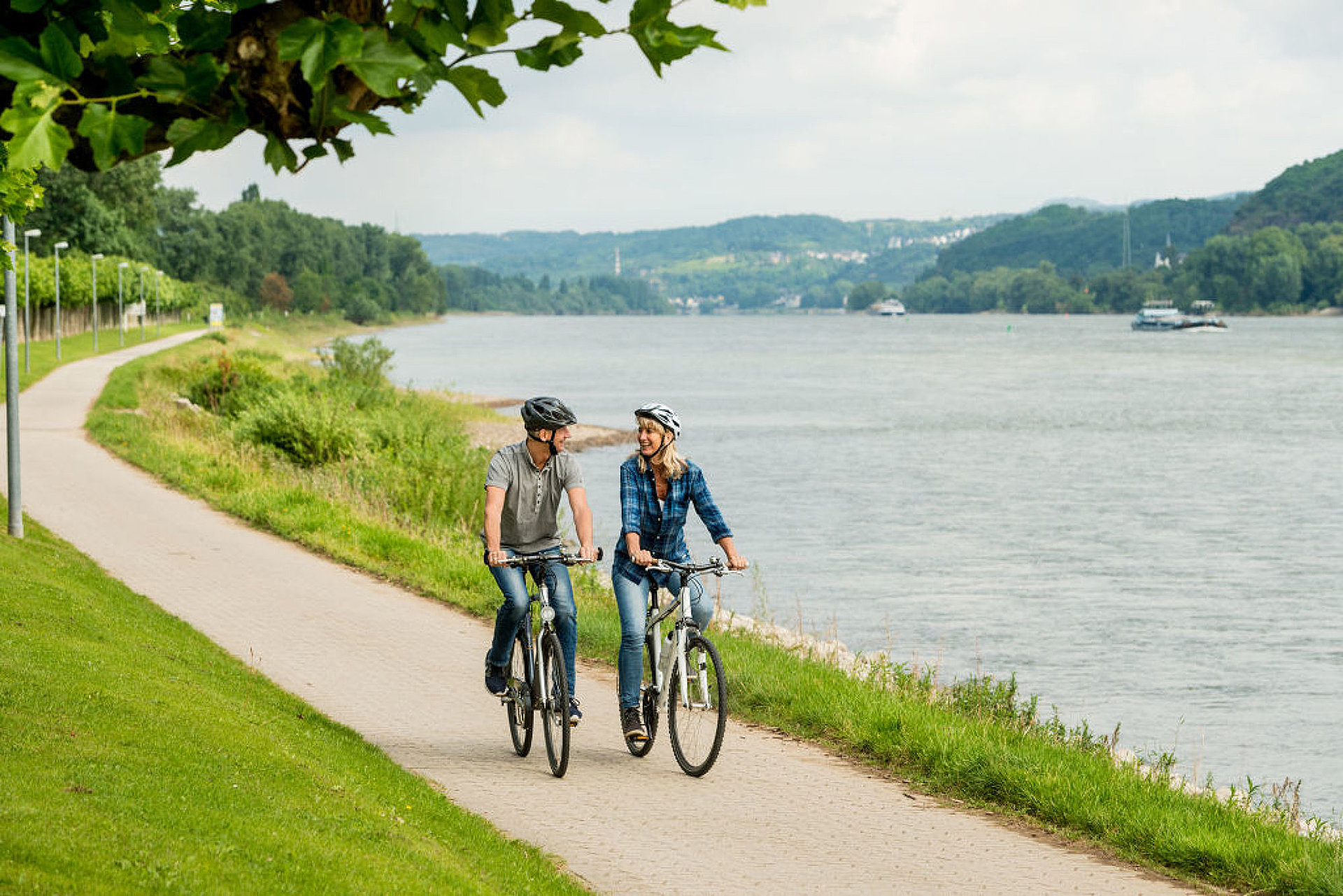 Paar beim Radfahren am grünen Rheinufer